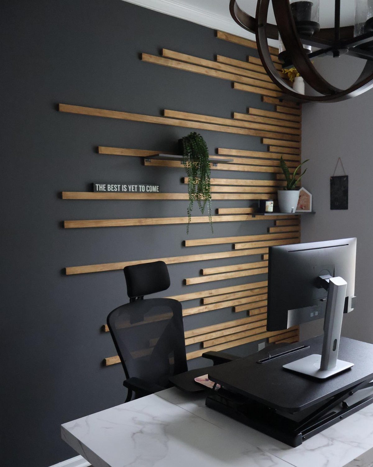 Horizontal wood slats on a dark grey wall with small black shelves and plants.