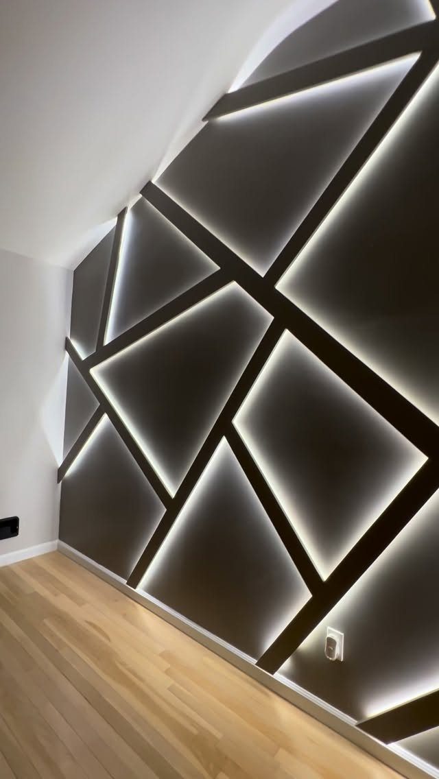 Geometric dark grey accent wall with glowing white LED strip lighting and black intersecting lines.