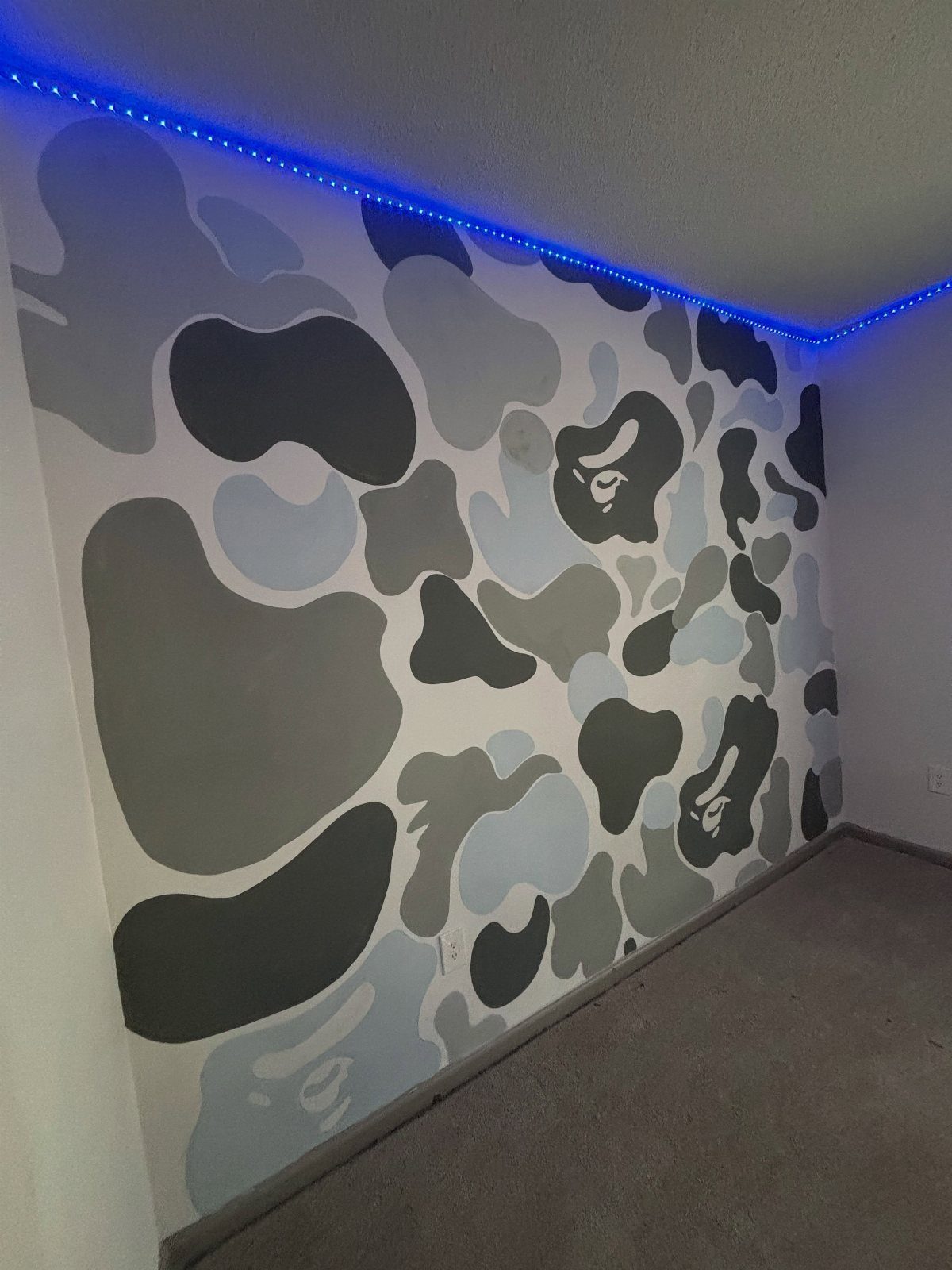 Camouflage patterned accent wall with blue LED lighting strip along the ceiling line.