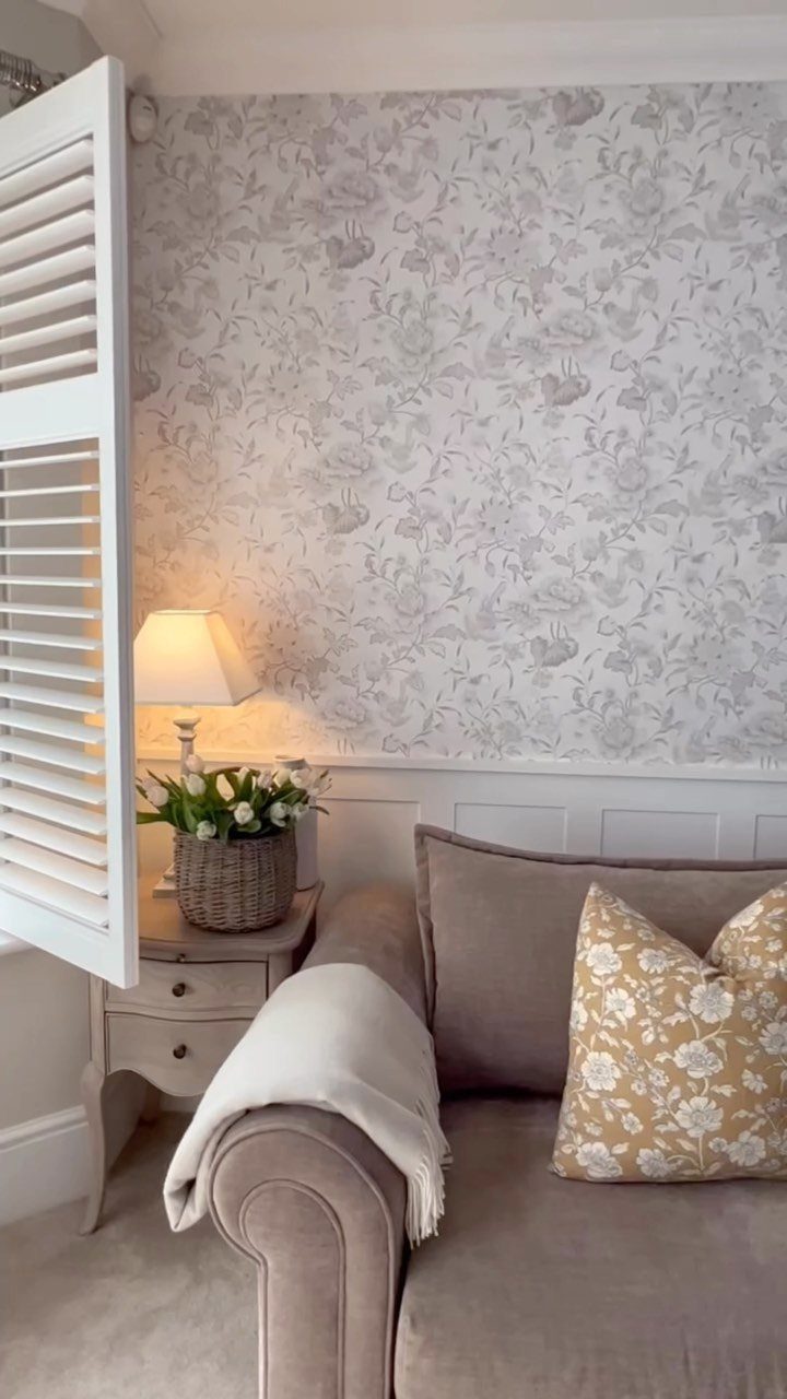 Floral patterned wallpaper on an accent wall behind a beige sofa and side table.