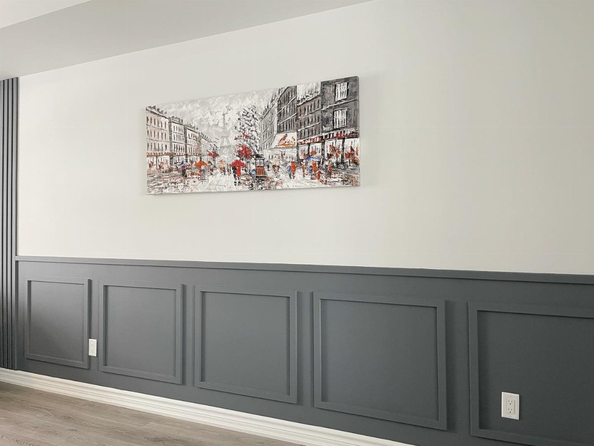 Grey wainscoting with rectangular molding panels installed on a white living room wall.