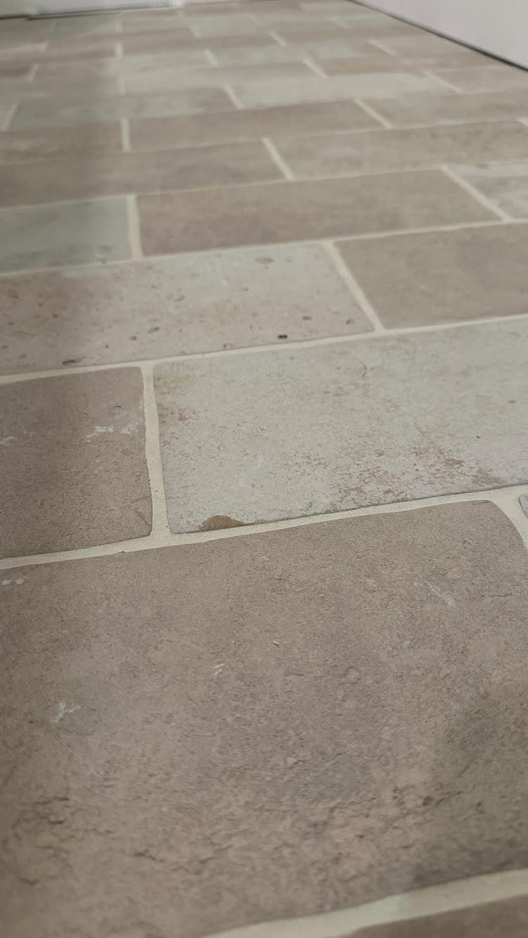 10 Affordable Flooring Ideas for Every Room in 2026 8 Light beige rectangular ceramic tiles with textured surfaces laid in a staggered pattern on a floor.