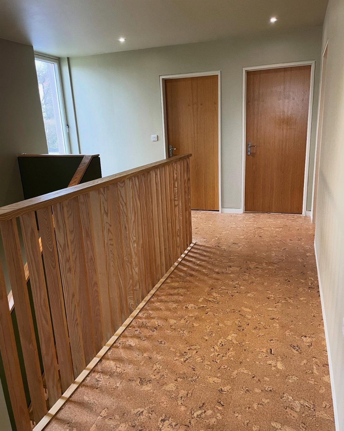 10 Affordable Flooring Ideas for Every Room in 2026 5 Tan textured cork flooring installed in a hallway with wooden doors and a banister.