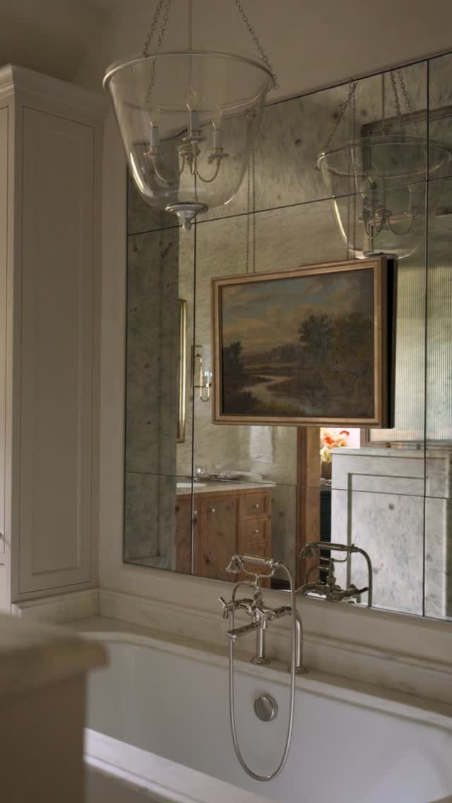 Antique mirror tiles with a distressed finish covering a bathroom wall above a white bathtub.