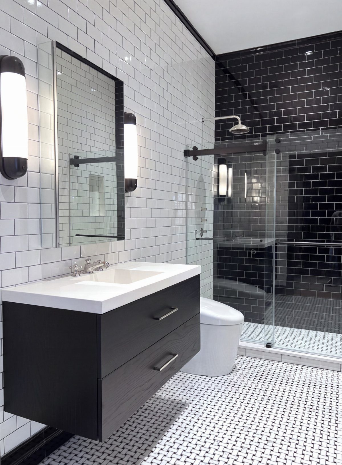 Modern bathroom with white subway tiles, black shower tiles, and patterned black and white floor tiles.