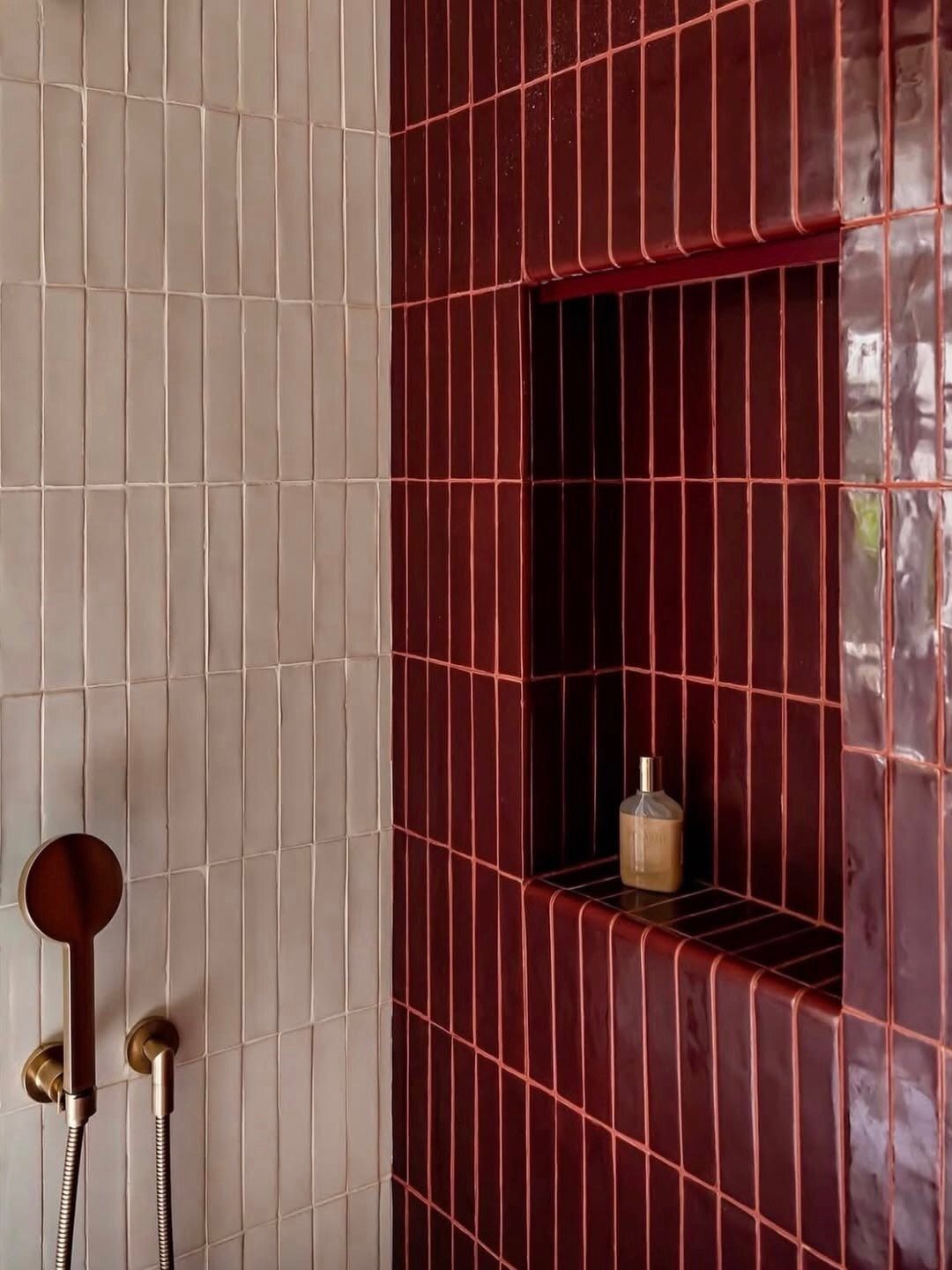 Burgundy and light grey vertical rectangular tiles in a modern shower setting.