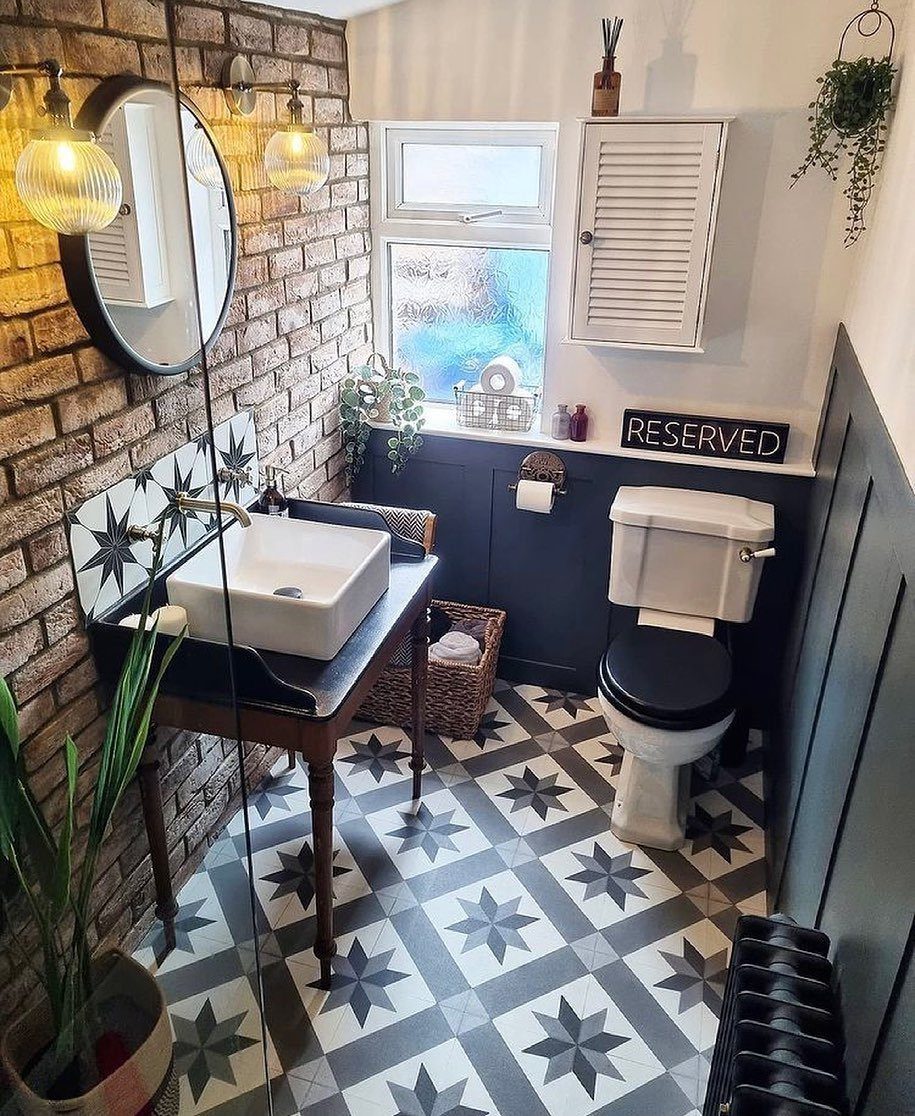 A small bathroom with a brown brick accent wall, white sink, and patterned star tiles.