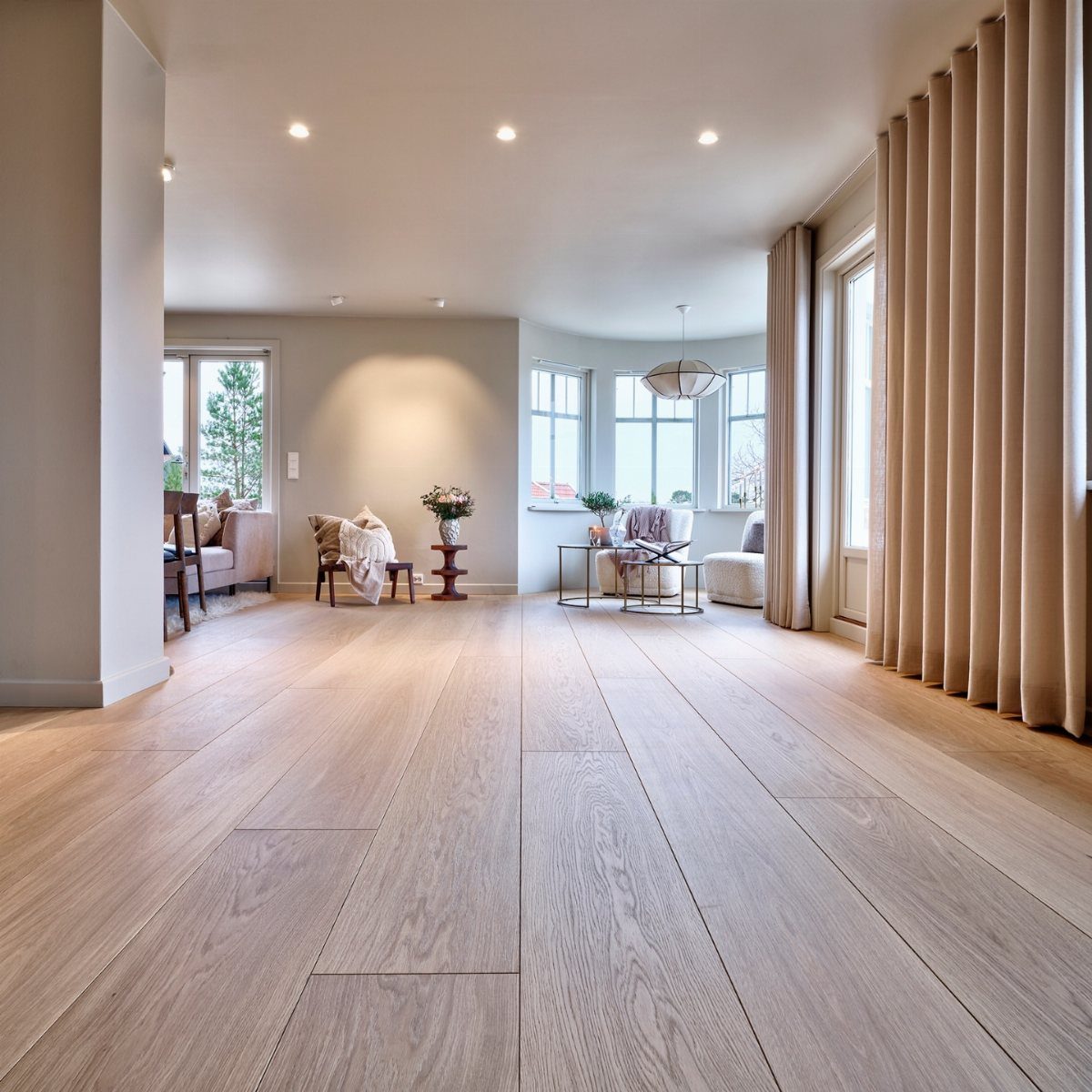 Cool Tone Wood Floors: 6 Mix-and-Match Ideas for Modern Matches 6 Light grey-toned wood plank flooring in a bright, modern living room with large windows.