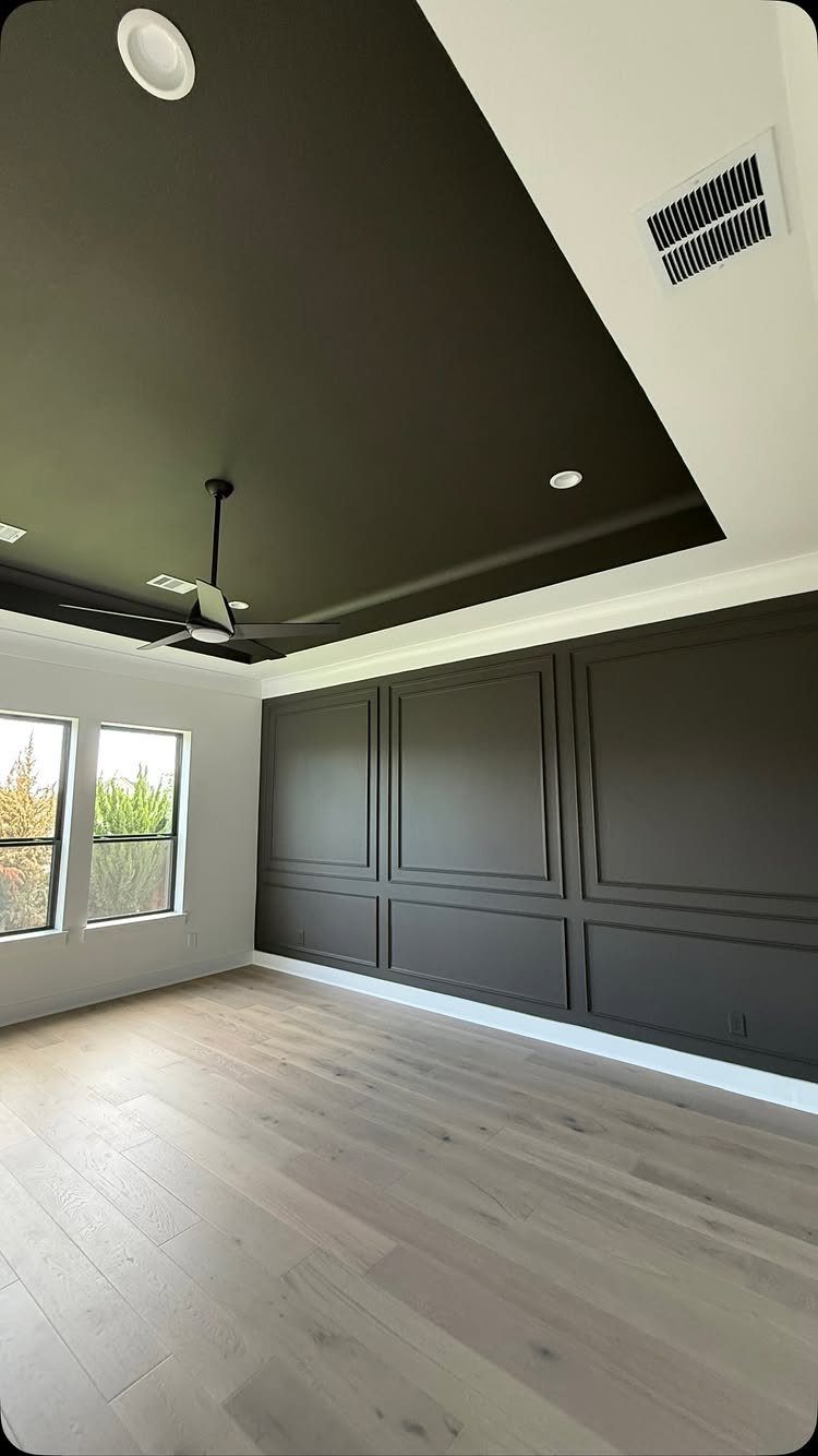 15 Feature Wall Ideas That Rely on Material, Not Just Color 10 Dark charcoal accent ceiling and paneled walls in a room with light wood flooring.