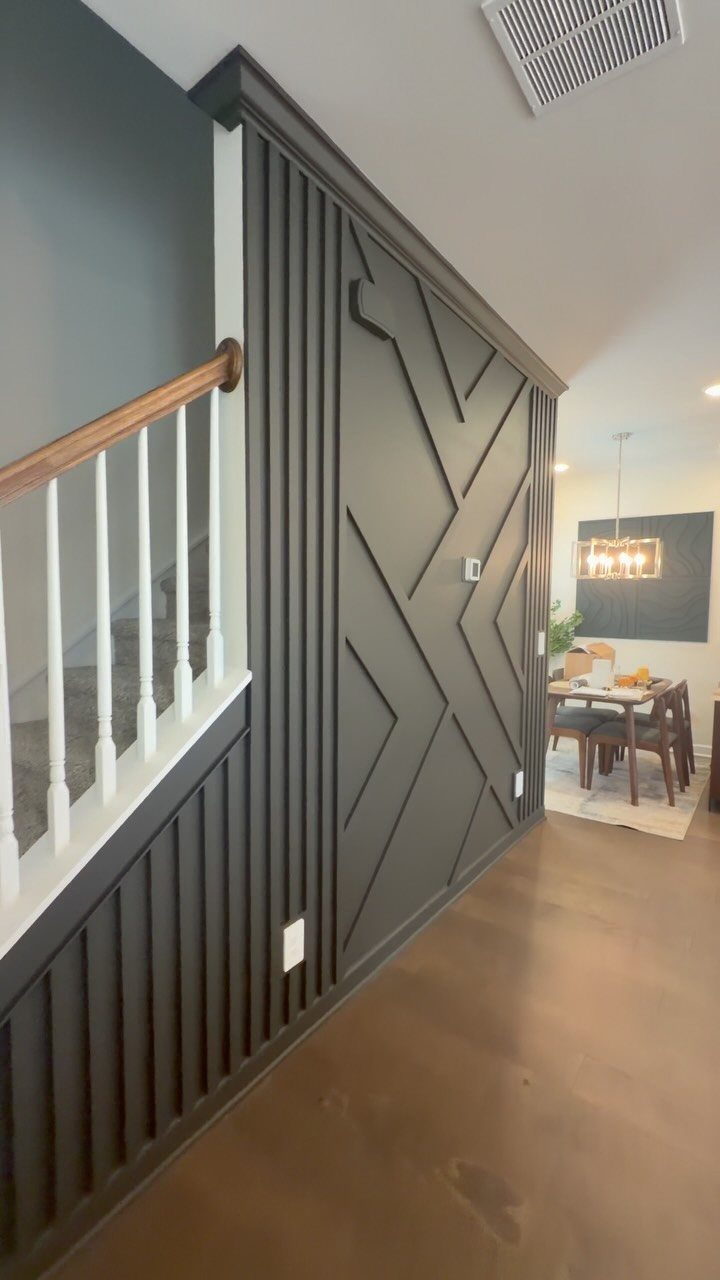 15 Feature Wall Ideas That Rely on Material, Not Just Color 11 Dark grey wall with raised geometric wooden slat patterns in a modern home hallway.