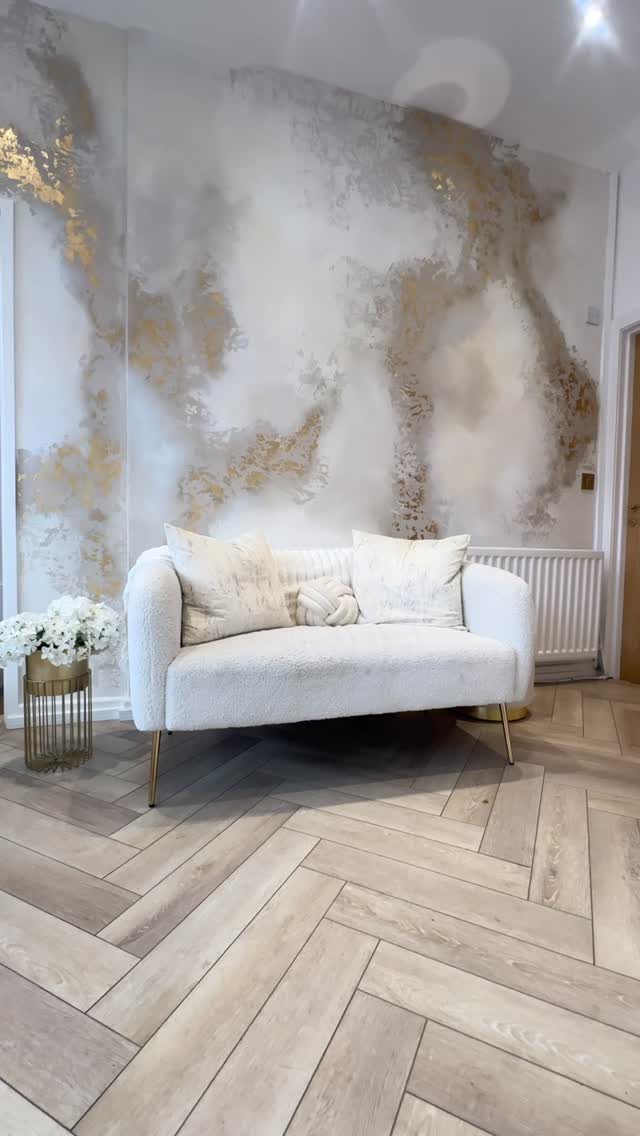 15 Feature Wall Ideas That Rely on Material, Not Just Color 1 White sofa positioned in front of a textured white and gold painted feature wall.