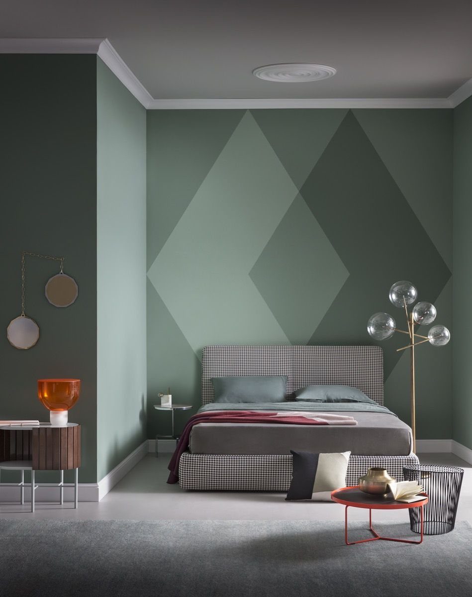 Sage green bedroom with a large diamond pattern accent wall and a grey bed.