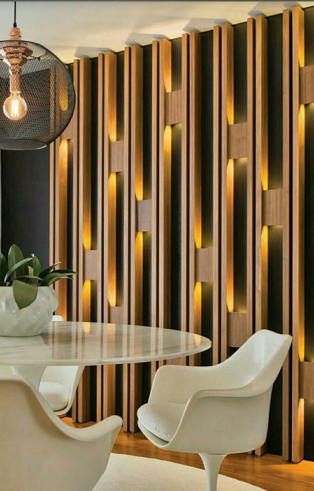 Vertical wooden slats with warm integrated lighting installed on a dark interior wall.