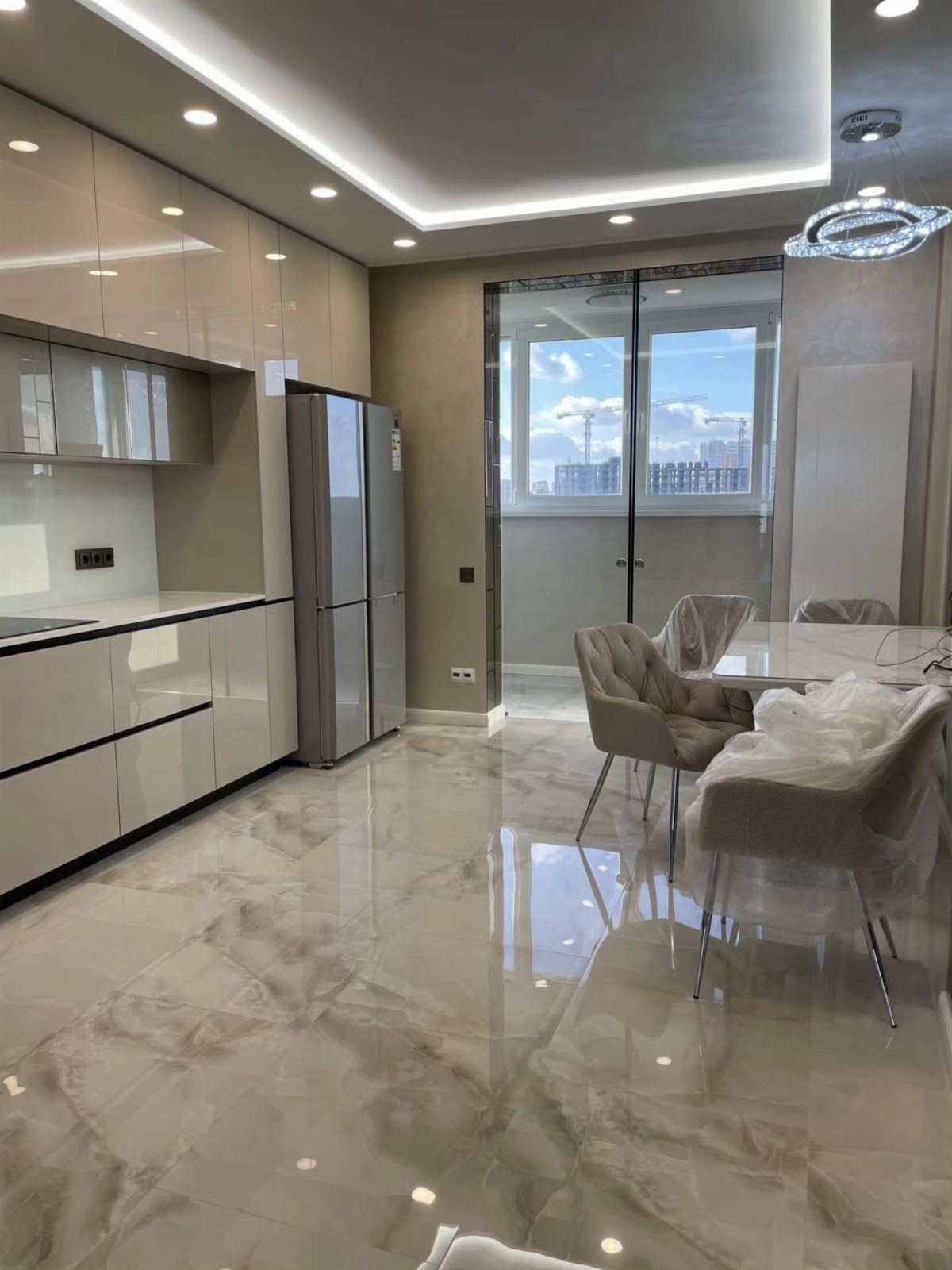 Kitchen Floor Colors: 14 Ideas for 2026 10 Large marble-effect floor tiles in a modern kitchen with white cabinets and dining furniture.