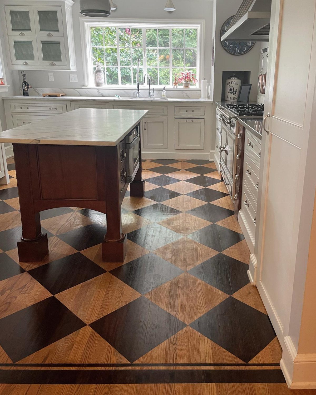 9 Kitchen Hardwood Flooring Ideas for Light to Bold Contrast 5 Checkerboard pattern hardwood flooring in a kitchen with a dark wood island and white cabinets.