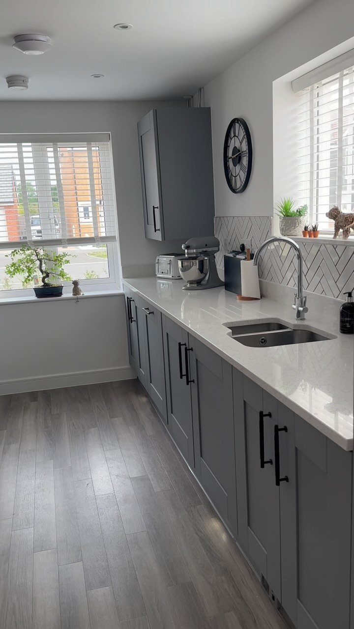 9 Kitchen Hardwood Flooring Ideas for Light to Bold Contrast 6 Gray wood-look plank flooring in a modern kitchen with gray cabinets and white countertops.