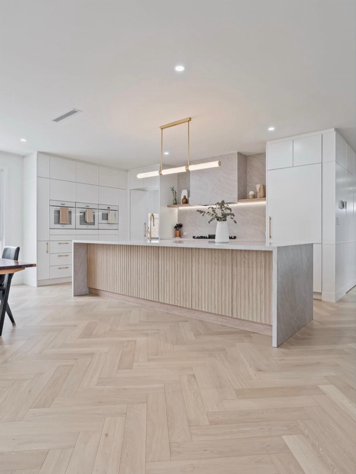 9 Kitchen Hardwood Flooring Ideas for Light to Bold Contrast 3 Light wood flooring in a herringbone pattern within a modern, bright kitchen setting.