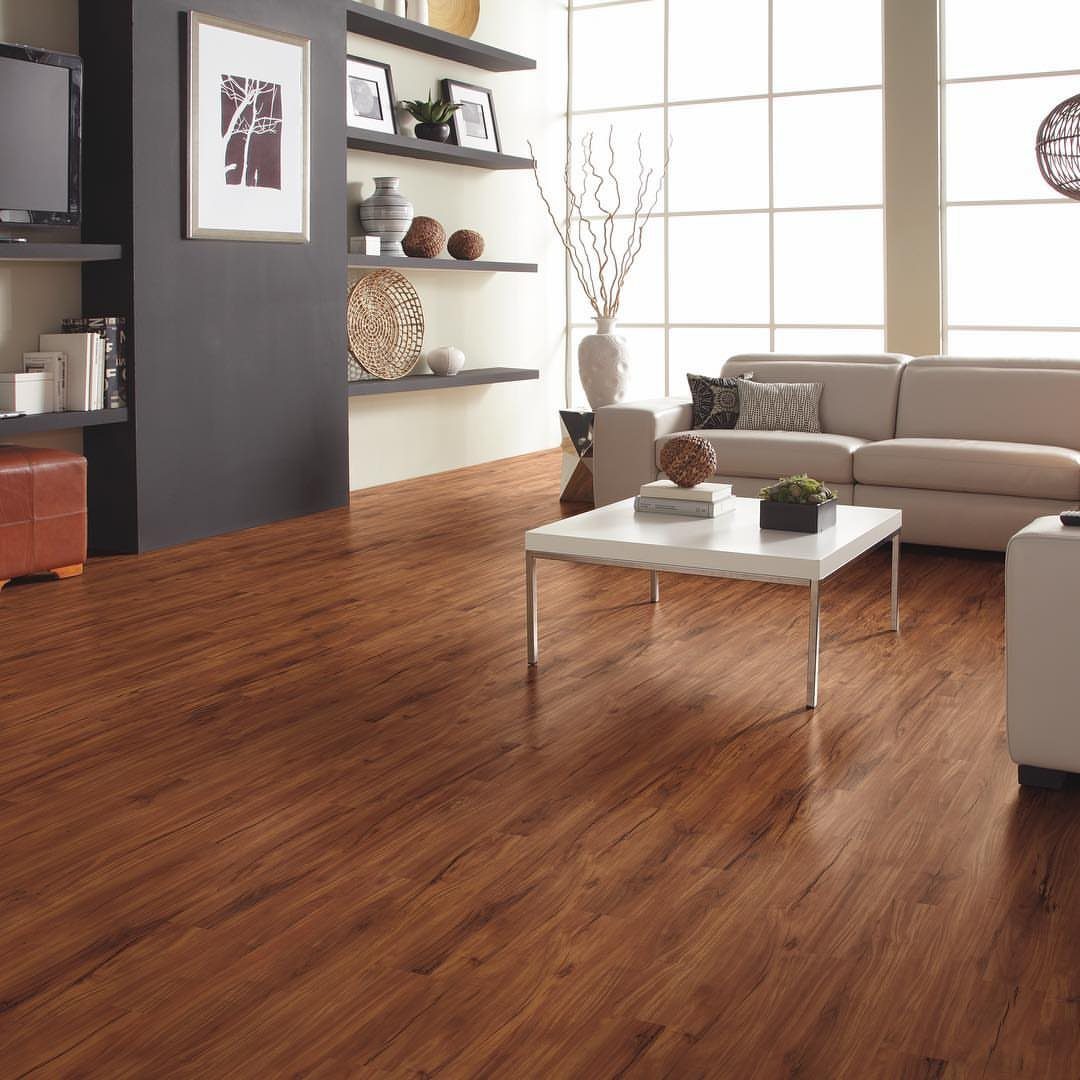 Most Popular Coretec Colors: 8 Best-Selling Flooring Picks 5 Warm wood plank flooring in a bright, modern living room with a beige sofa and white coffee table.