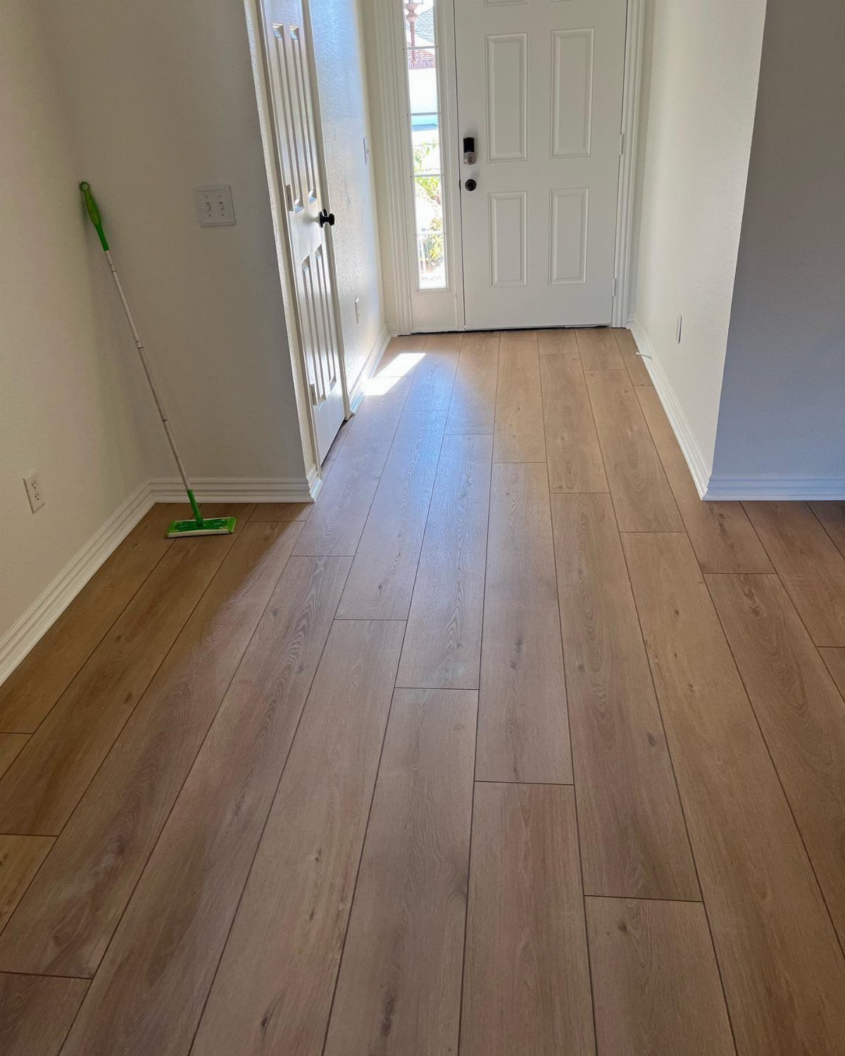 Most Popular Coretec Colors: 8 Best-Selling Flooring Picks 6 Light brown wood-look flooring planks installed in a hallway leading to a white door.