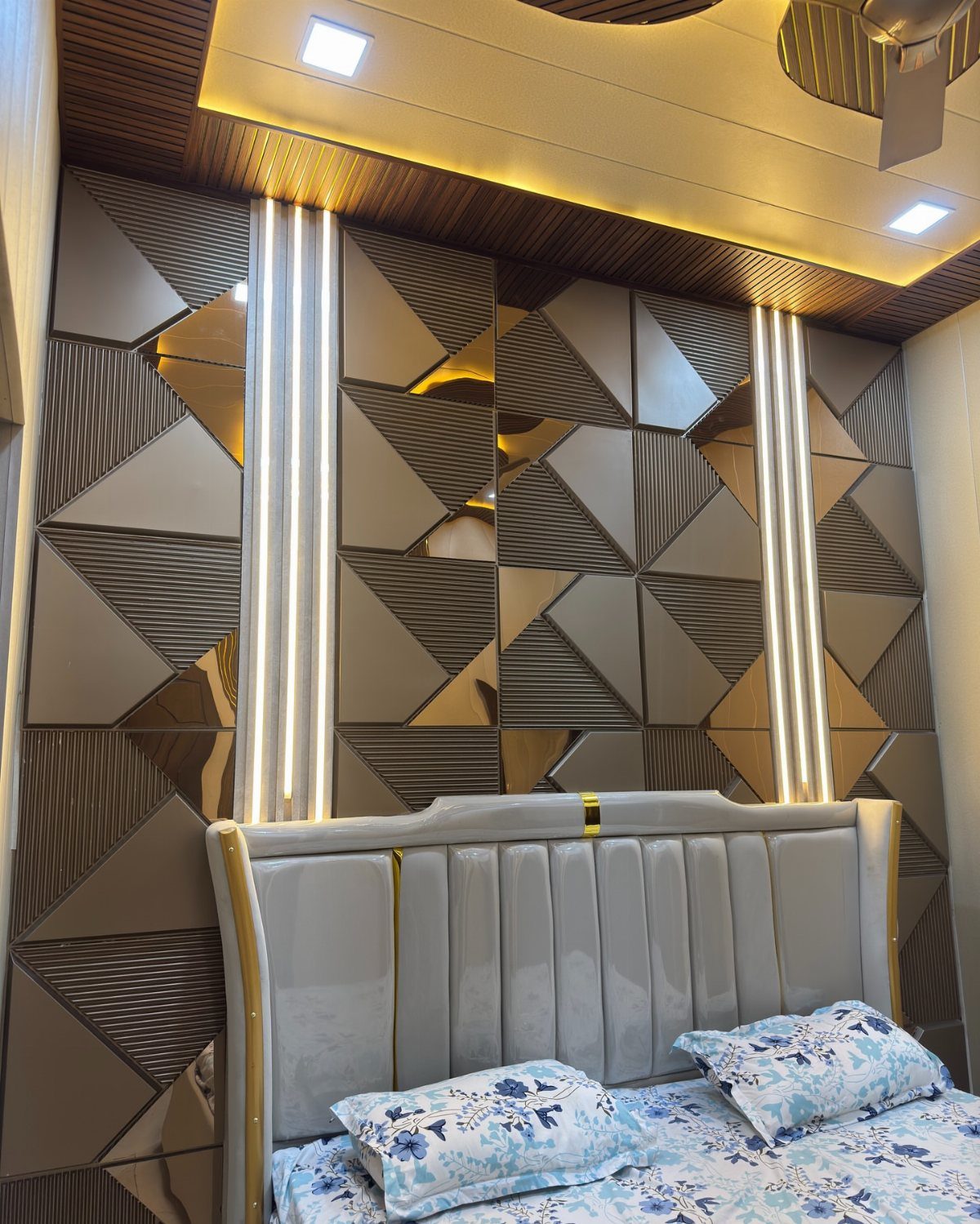 Geometric patterned PVC wall panels with vertical light strips behind a white bed headboard.