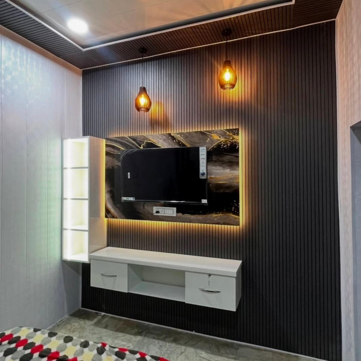Dark fluted wall panels with a backlit marble TV mount and hanging pendant lights.