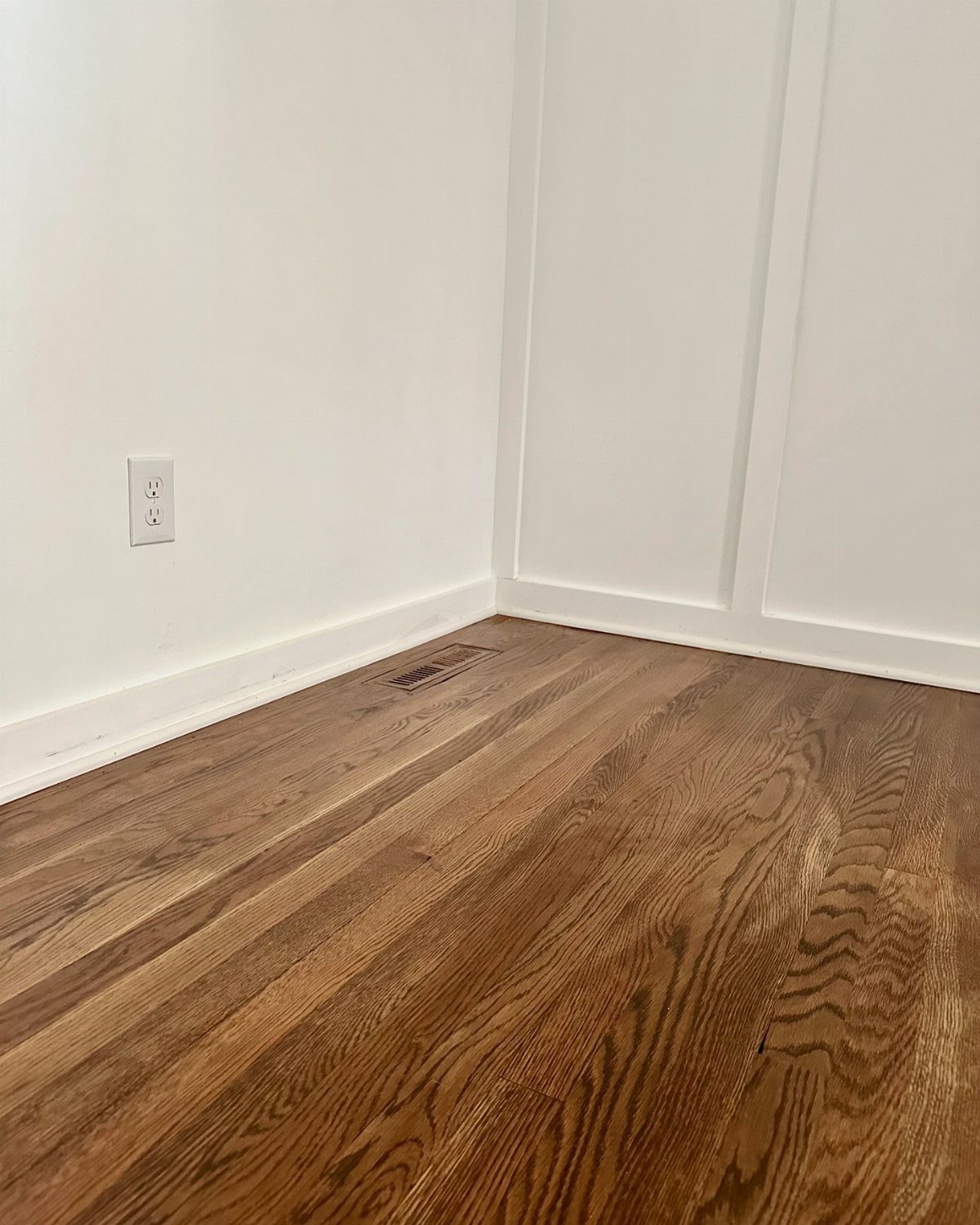 Hardwood flooring with prominent swirling grain patterns installed in a room with white walls.
