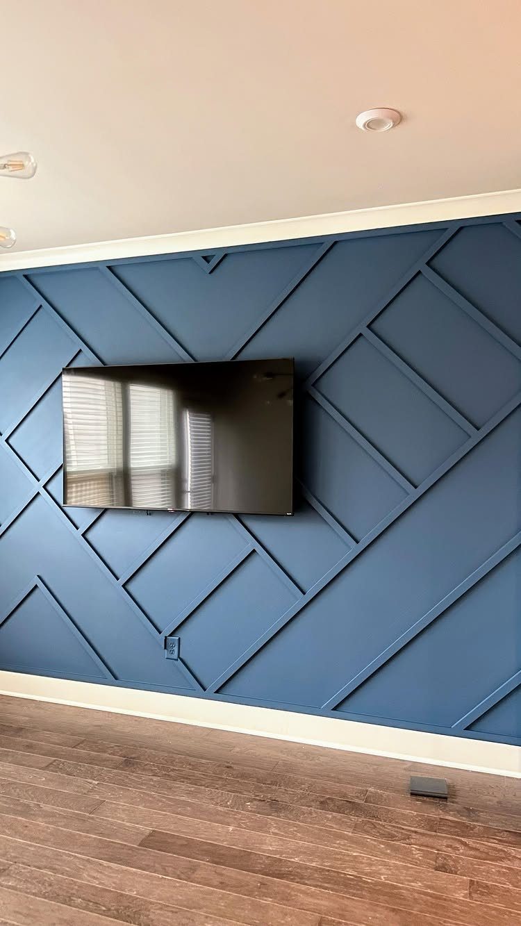A blue geometric patterned accent wall with a television mounted in the center.