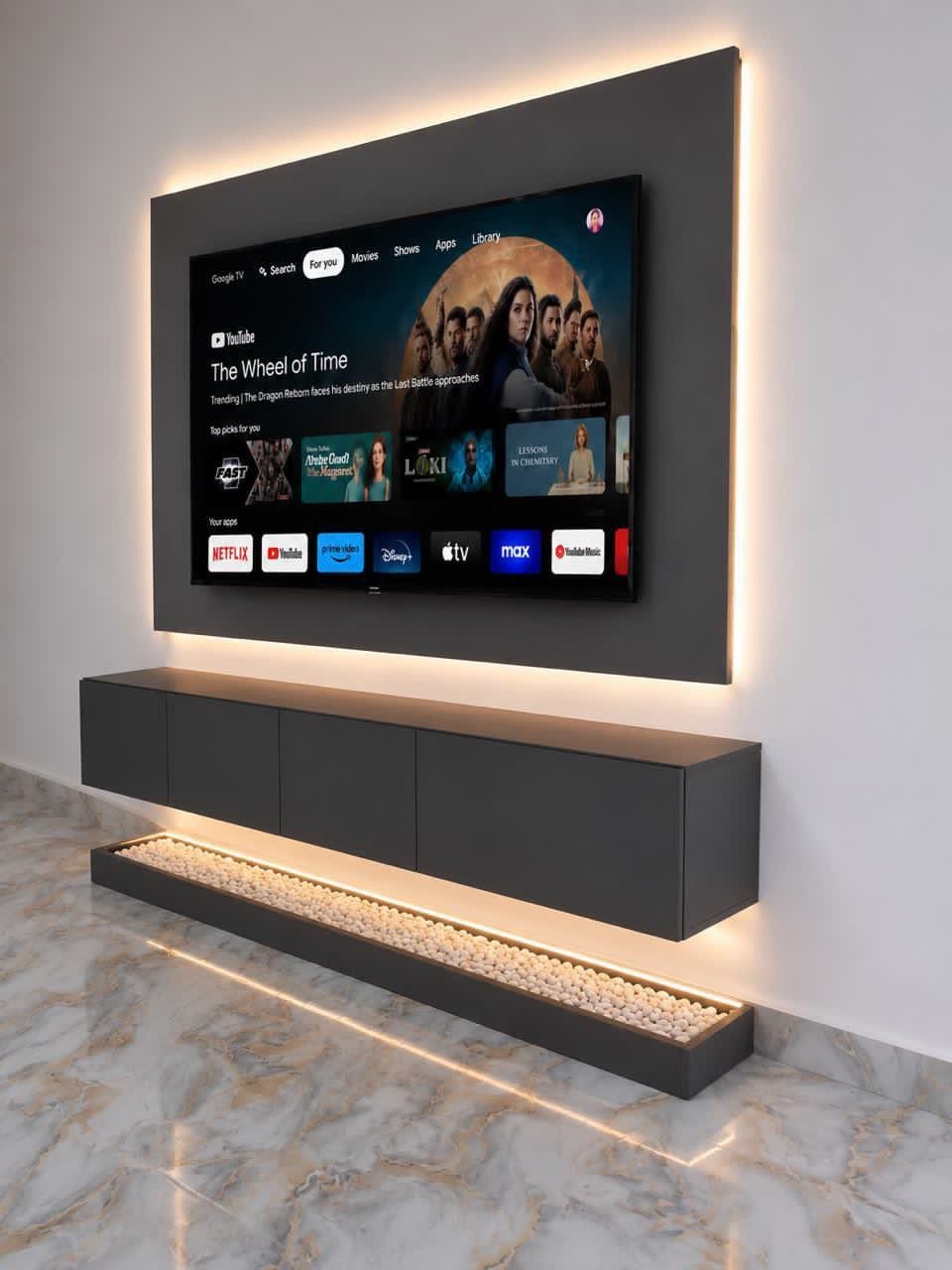 A dark grey floating console mounted on a wall beneath a large television with LED lighting.