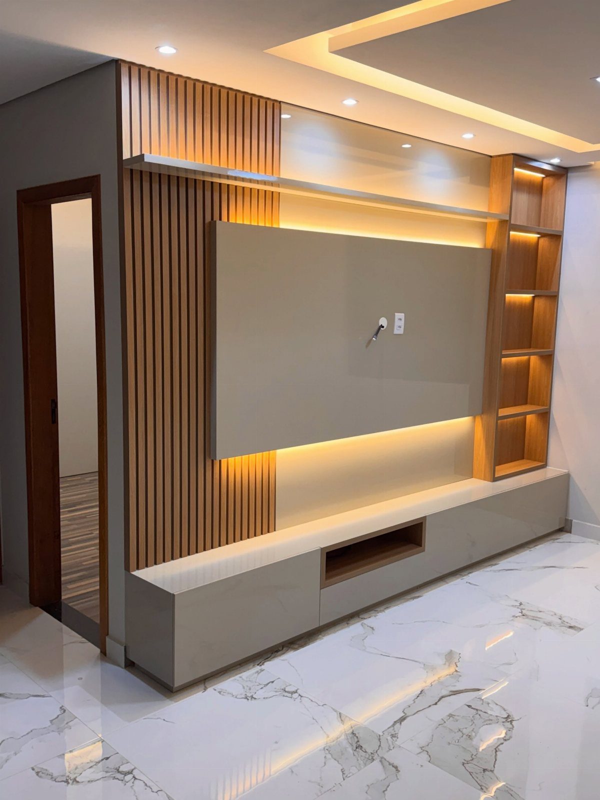 A modern TV wall design with wood slats, built-in shelving, and warm integrated LED backlighting.