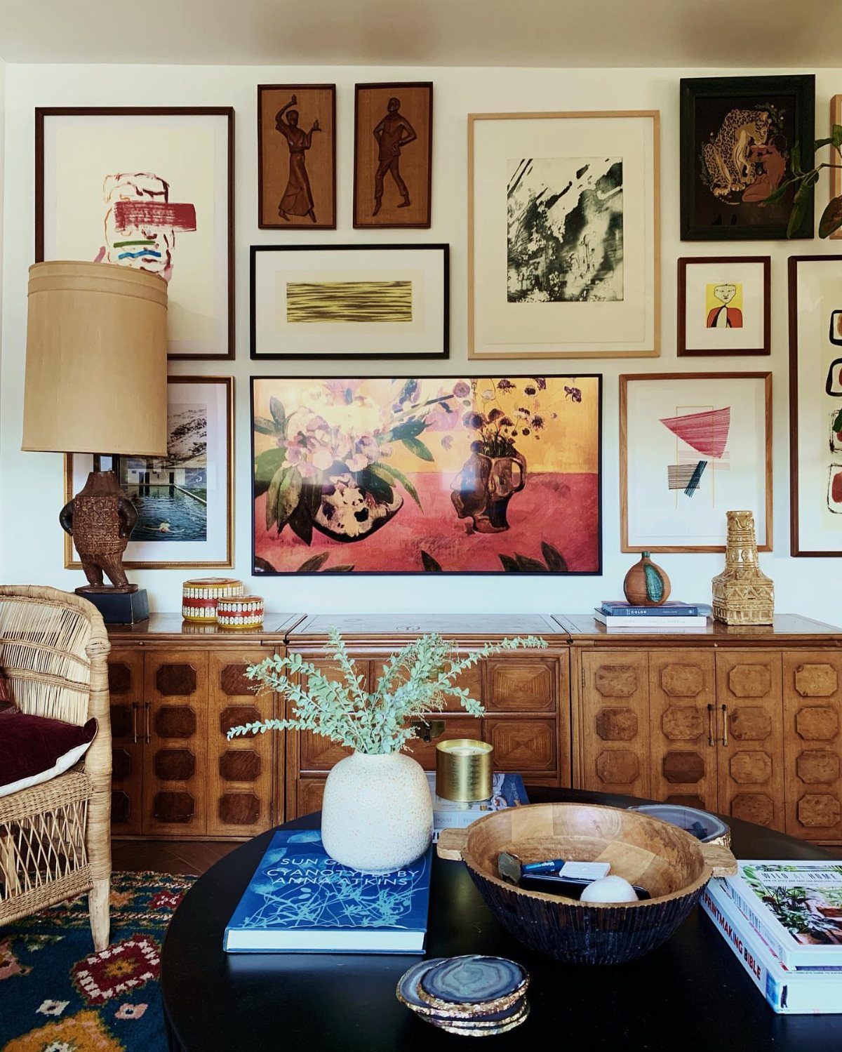 A television surrounded by a diverse collection of framed art pieces on a white wall.