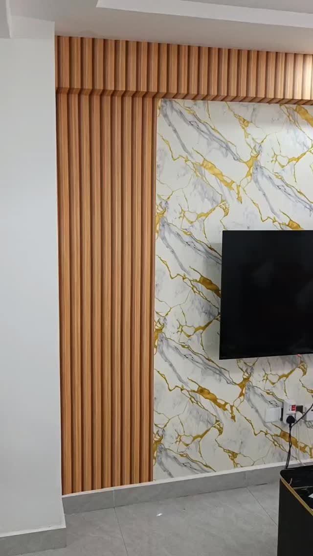 Television mounted on a white and gold marble-patterned wallpapered accent wall with wood slats.