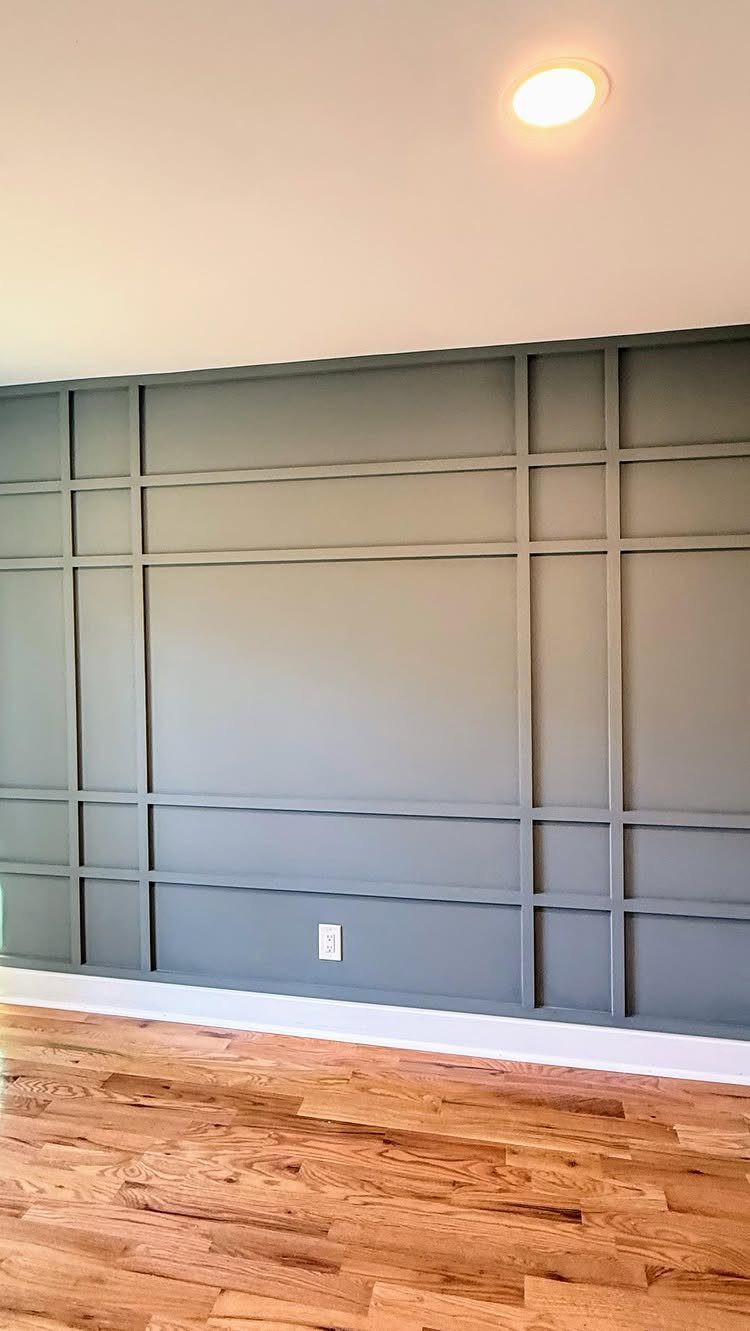 8 Wall Molding Design Ideas for Rooms That Need More Structure 4 Grey wall featuring a large rectangular grid moulding design above hardwood floors.