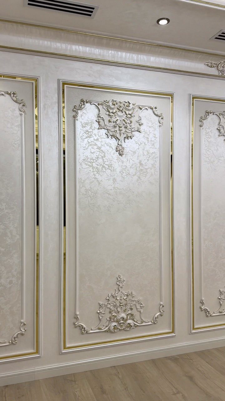 8 Wall Molding Design Ideas for Rooms That Need More Structure 6 Ornate white wall panels with gold trim and decorative plaster carvings on a wall.