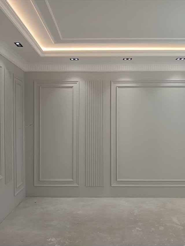 8 Wall Molding Design Ideas for Rooms That Need More Structure 2 White walls with decorative picture frame moulding and vertical fluted panels in a room with recessed lighting.