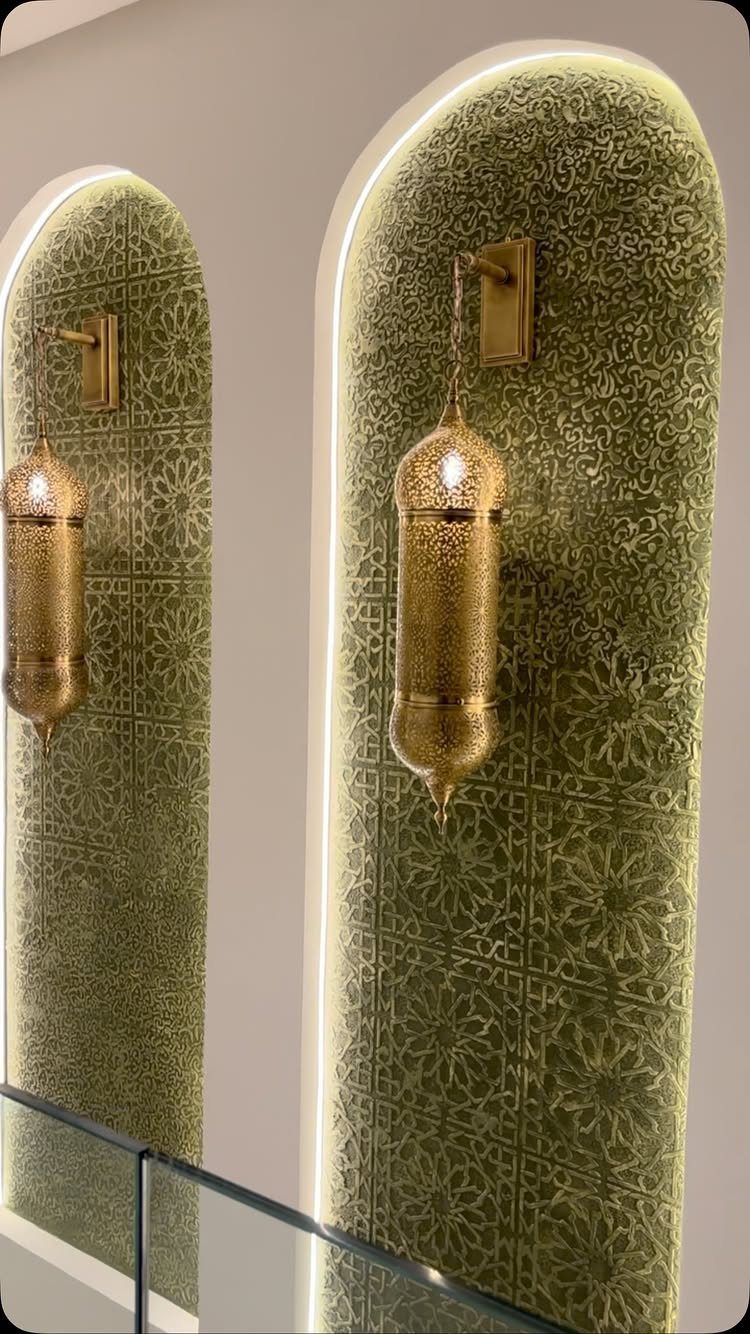 Two arched alcoves with green patterned wall panels and gold lantern sconces.