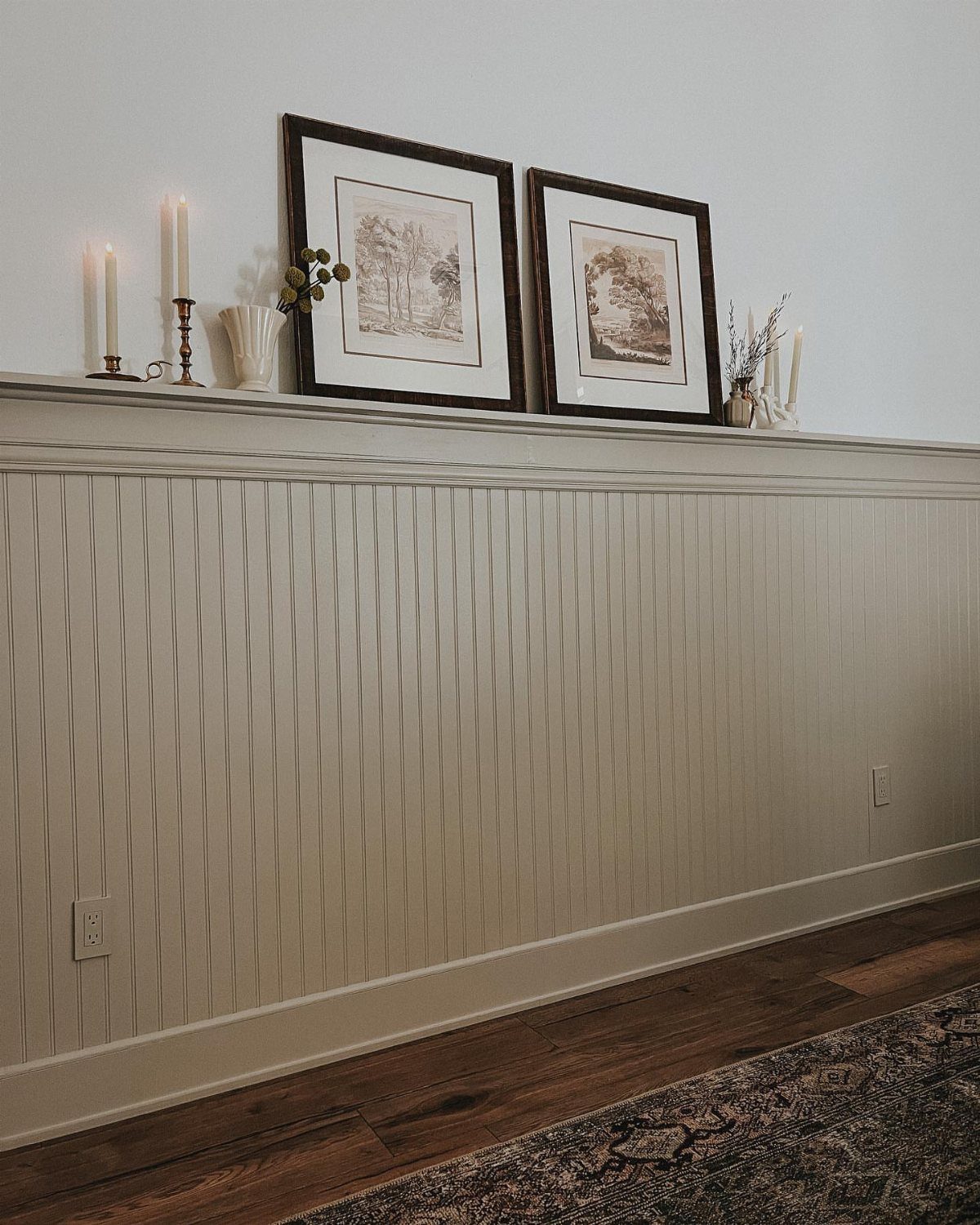 Beadboard wainscoting with vertical grooves on a wall above dark wood flooring.