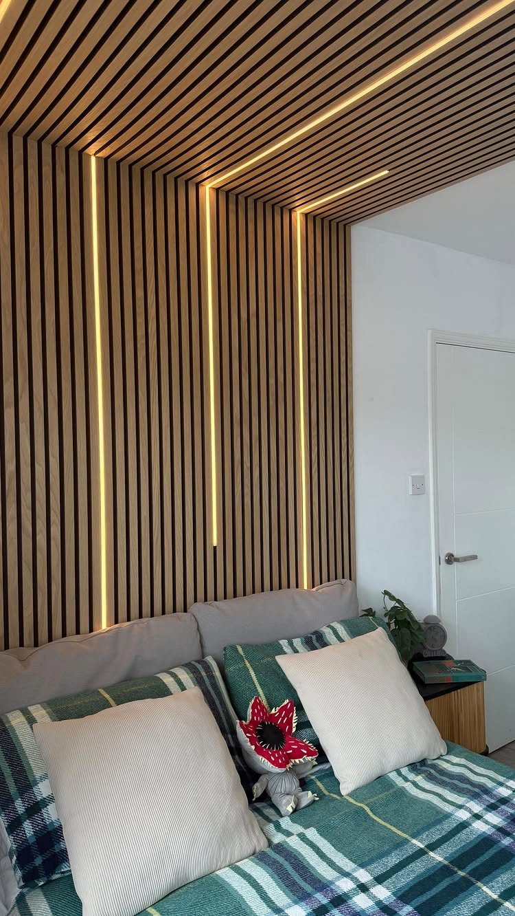 Light wood slat wall and ceiling with integrated warm LED strip lighting above a sofa.