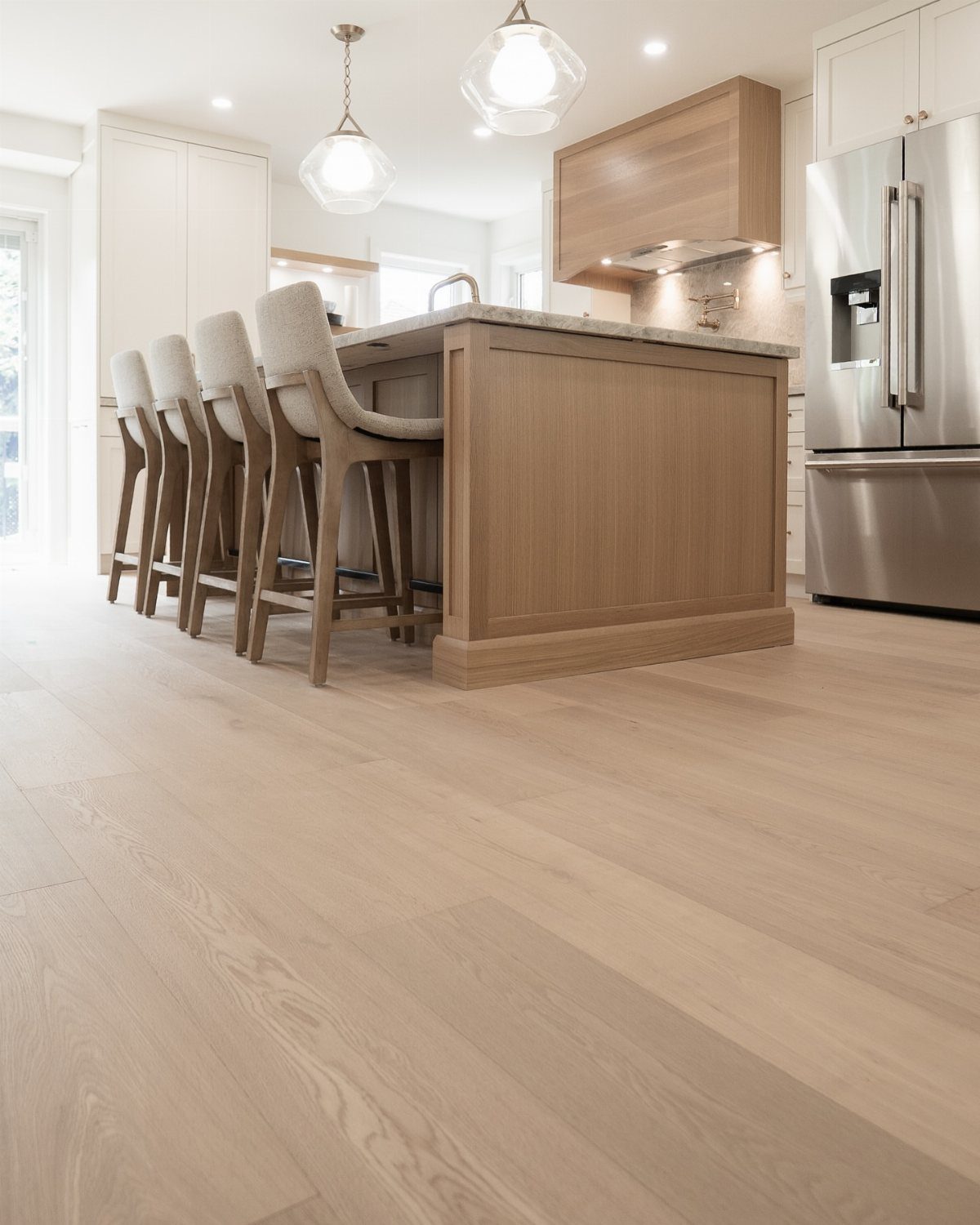Light wood flooring seamlessly matching the wooden kitchen island and cabinetry in a modern home.